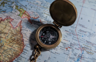 an open compass laying on a map of the world. 