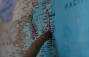 someone pointing to Tokyo, Japan on a map.